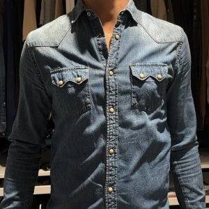 Zara Blå jeansskjorta. S - Zara. Snygg blå jeansskjorta med knappar och två bröstfickor. Skjortan har långa ärmar och en klassisk krage. Perfekt för en avslappnad stil. Storlek S