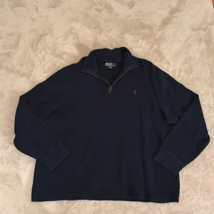 Mörkblå tröja från Ralph Lauren - Säljer en stilren mörkblå tröja från Ralph Lauren med dragkedja vid halsen. Tröjan har långa ärmar och en liten röd logotyp broderad på bröstet. Perfekt för en avslappnad och snygg look. Hör av dig vid funderingar och pris kan diskuteras vid snabb affär mvh Malte 