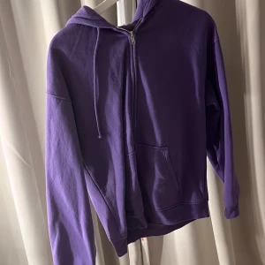 Lila hoodie med dragkedja - Säljer en snygg lila hoodie med dragkedja och huva. Tröjan har långa ärmar och en praktisk ficka framtill. Perfekt för en avslappnad stil.