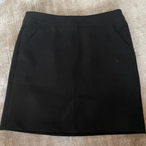 Svart kortkjol från Vero Moda - Snygg svart kortkjol från Vero Moda i fuskmocka. Kjolen har en stilren design med en dragkedja bak och lite stretchig i materialt samt fickor på sidan. Den är i mycket bra skick och passar till alla tillfällen. 🖤