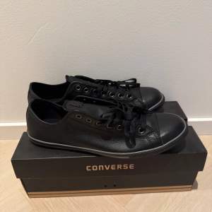 Säljer ett par svarta Converse sneakers i skinn. De har klassisk snörning och är helt nya med originalförpackning kvar. Perfekta för både vardag och festliga tillfällen. Storleken är normal och de passar bra till alla säsonger.