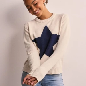 Vit stickad tröja med blå stjärna - Superfin vit stickad tröja med en stor blå stjärna på framsidan. Perfekt för både höst och vinter! Den har långa ärmar och ribbade kanter som ger en mysig känsla. Använt fåtal gånger