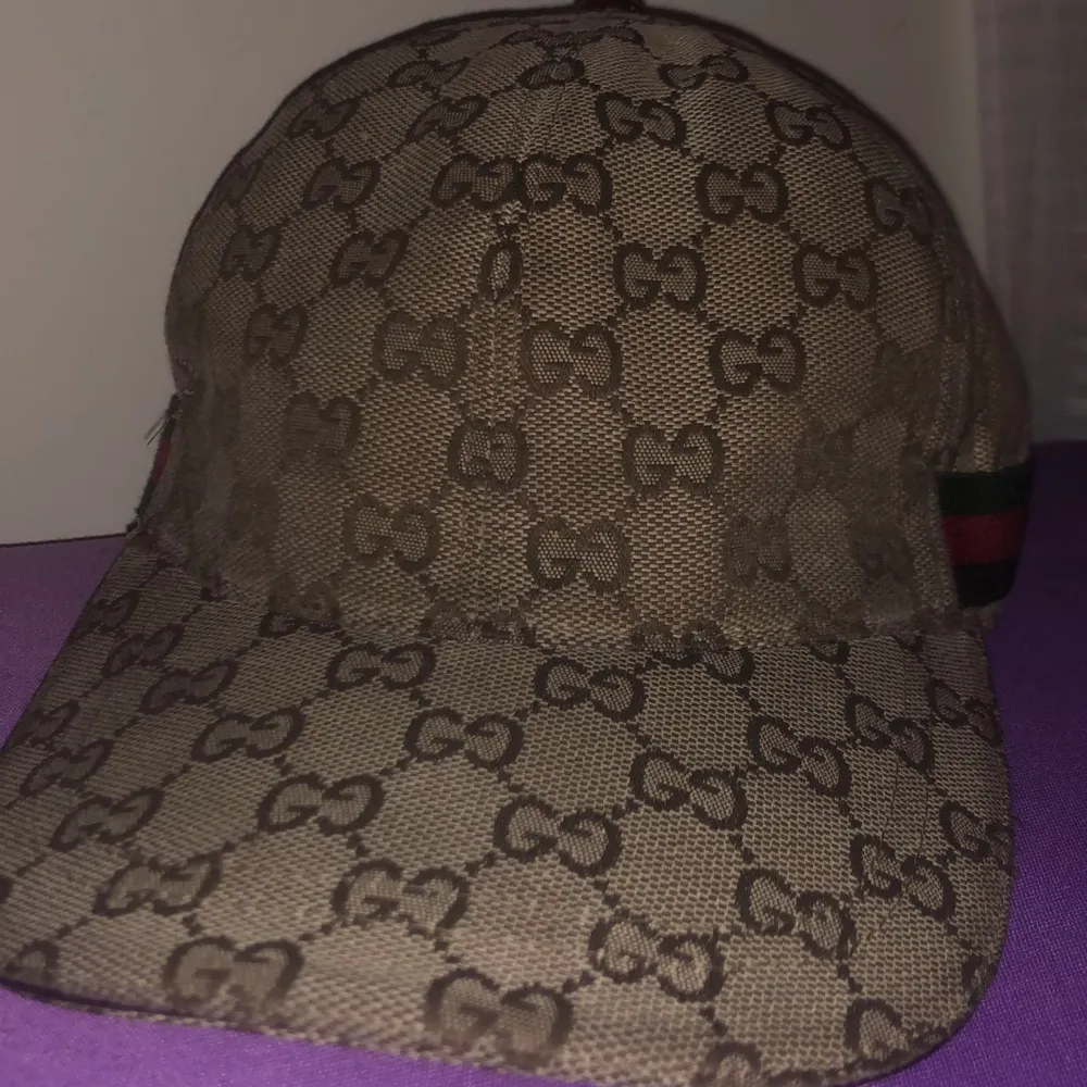 Snygg beige keps med klassiskt monogrammönster och röd-gröna detaljer på sidan. Kepsen har en justerbar rem baktill för perfekt passform. Perfekt för att ge din outfit en lyxig touch! För mer info skriv och priset kan diskuteras vid snabbaffär!!!. Accessoarer.