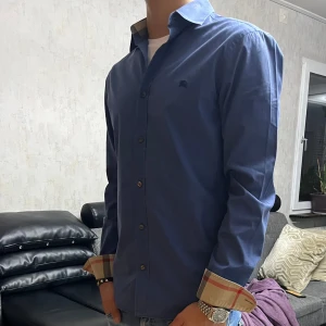 Burberry skjorta. - Säljer en snygg blå skjorta från Burberry i bra skick. Perfekt för både vardag och fest! SJÄLVKLART ÄKTA ALLT VI SÄLJER ÄR ÄKTA.