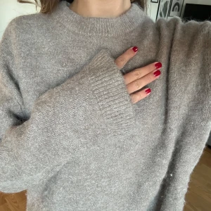 Beige stickad tröja - Mysig beige stickad tröja perfekt för kyliga dagar. Den har en klassisk rund hals och långa ärmar med ribbade muddar. Tröjan är i ett mjukt material som känns skönt mot huden. Passar både till vardags och lite finare tillfällen.