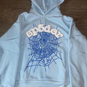 Hoodies från Sp5der - Två coola hoodies från Sp5der i storlek M. Den ena är ljusblå och den andra lila, båda med ett spindelnätsmönster och texten 'sp5der' på framsidan. Perfekta för en avslappnad stil med en touch av streetwear. Tillverkade i mjuk bomull för extra komfort. Säljer en för 1500kr och 2 för 2000kr