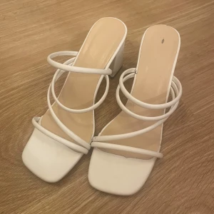 Vita klackskor med remmar - Använda 1 gång så i mycket fint skick! Ca 7cm klack och i strl 36 men skulle säga att de passar 37 också. Köpta för 250 men säljer billigt o är öppen för prisförslag