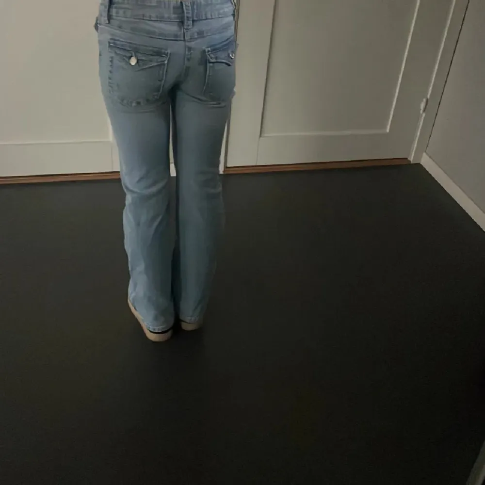 Säljer ett par ljusblå jeans från Gina Tricot i storlek 152. De har en bootcut-stil och är lågmidjade med knappar och dragkedja framtill. Perfekta för en avslappnad vardagslook! 🦋. Jeans & Byxor.