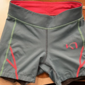 Blå/Gröna träningsshorts med rosa detaljer - Säljer ett par träningsshorts med coola rosa och gröna sömmar. Säljer då de blivit för små men har älskat dem. Kolla på bilderna för att se skicket. Dem är i xs men skulle säga att de passar xxs mer.