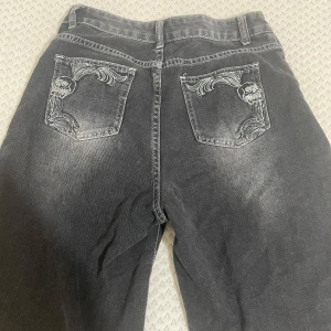 Emo y2k shorts  - Coola svarta jeans med unikt dödskallebroderi på bakfickorna. De har en sliten look som ger en edgy stil. Perfekta för en avslappnad och rockig outfit. Passar bra till både vardag och fest!