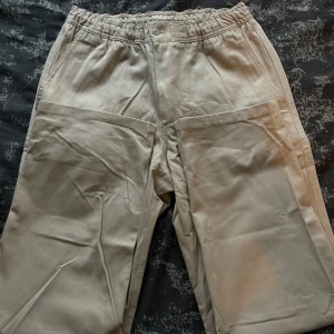 Beige mjukisbyxor - Säljer ett par bekväma beige mjukisbyxor med elastisk midja och praktiska fickor. Perfekta för en avslappnad dag hemma eller en snabb tur till affären. Byxorna har en loose passform som ger en skön känsla. De är i bra skick och redo för en ny ägare!