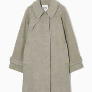 Beige kappa från COS - Säljer en elegant beige kappa från COS i ullblandning. Den har en klassisk krage och knappar framtill. Perfekt för höst och vinter med sin stilrena design och långa ärmar. Passar både till vardags och festliga tillfällen. Nypris:3300kr. 