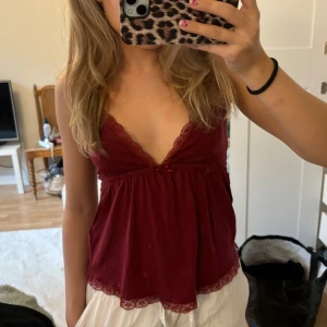 Vinröd linne med spetsdetaljer - Säljer ett superfint vinrött linne med spetsdetaljer. Det har en v-ringad design och smala axelband. Passar perfekt till både vardag och fest! Endast anvönd 1 gång!!🤍🩷