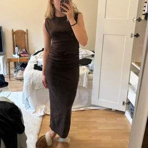 Maxiklänning - Säljer en snygg brun ärmlös klänning i ett stretchigt material. Den är figurnära och perfekt för både vardag och fest. Klänningen har en enkel design som gör den lätt att styla med olika accessoarer. Passar perfekt för höst och vår! Lappen är borttagen, men har aldrig använt klänningen endast testad!🩷
