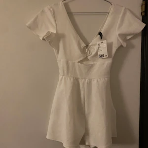 Vit kort klänning med shorts i  - Säljer en superfin vit kort klänning med shorts i . Klänningen har korta ärmar och en v-ringad design som ger en elegant touch. Perfekt för sommarens alla fester eller en dag på stan. Helt ny med tag kvar!