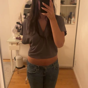 Grå croppad t-shirt - Säljer en grå croppad t-shirt med v-ringning. Perfekt för en avslappnad stil och passar bra till jeans. T-shirten har korta ärmar och är i ett mjukt material💞