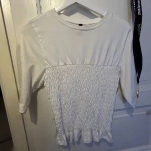 Vit ribbad topp från hm - Säljer en söt vit topp med ribbad design och trekvartsärmar.