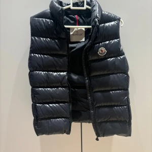 Svart moncler väst - Säljer min fina moncler väst då den inte  kommer till användning tyvärr🥲❤️ Storlek 14 years old tjejer men passar bra i längden för mig som är 167cm🥰 Ser mörkblå ut men den är svart!! Använd max 5 gånger!  Kvitto finns Beställd från monclers egna hems