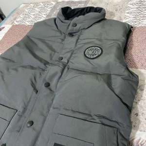 Canada Goose väst - Säljer en snygg grå från Canada Goose i nytt skick.  Perfekt för de kommande kyliga dagar och har praktiska fickor framtill. En helt ny vest som är i storlek XS men passar som S. Priset kan alltid diskuteras!