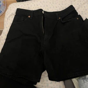 Svarta jeansshorts - Säljer ett par svarta jeansshorts i bra skick från monki. De har en klassisk design med dragkedja och knappar framtill. Perfekta för både vardag och fest! 🖤