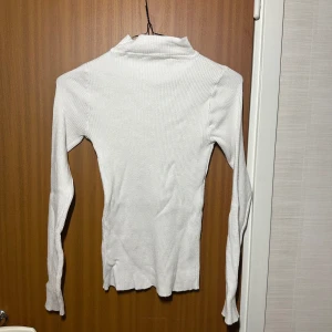 Vit stickad polotröja - Använd två/tre gånger, inga skador, varm och skön tröja, perfekt för höstväder. Tröjan går att kombinera med många plagg och är lätt att styla. Perfekt bas-plagg om man gillar stilen lager på lager, funkar även utmärkt att ha bara som den är! 