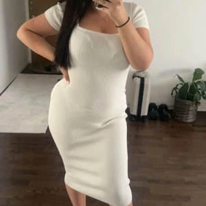 Vit ribbad klänning - Säljer en superfin vit ribbad klänning med korta ärmar. Den har en tight passform som framhäver figuren och är perfekt för både vardag och fest. Klänningen är gjord i ett mjukt och stretchigt material som gör den bekväm att bära hela dagen.