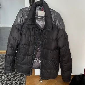 Moncler Chevalier Giubbotto - Säljer en snygg svart dunjacka från Moncler i ok skick. Den är perfekt för vintern med sitt varma och puffiga material. Modell chevalier giubbotto, size 3 passar perfekt på mig som e 175.