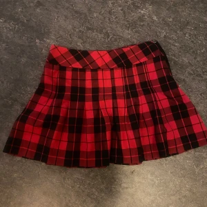 Rutig kjol från Lindex - Säljer en superfin rutig kjol från Lindex i rött och svart. Den har en vintage stil och kan stylas både upp och ner beroende på tillfälle. Passar perfekt för en cool och trendig outfit!