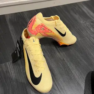 Säljer ett par grymma gula Nike fotbollsskor i nytt skick. De har en snygg svart swoosh och coola rosa detaljer på hälen. Skorna är designade för att ge bra grepp på planen med en orange sula. Perfekta för fotbollsspelare som vill sticka ut! PRIS KAN DISKUTERAS 