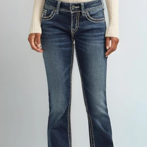Blå jeans från Silver Jeans Co. - Säljer ett par snygga blå jeans från Silver Jeans Co. i mycket bra skick. De har en bootcut-stil och är dekorerade med coola broderier på bakfickorna. Jeansen har en klassisk femficksdesign och en knapp med snyggt mönster. Perfekta för både vardag och fest! ORGINAL PRIS: Ca. 800kr  miss me liknande 2000s märke från Kanada. 