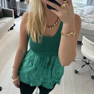 Grön ärmlös topp i satin och viskos - Snygg grön ärmlös topp i en mix av satin och viskos. Perfekt för sommardagar eller en avslappnad fest. Den har en smickrande passform med ett stickat mönster upptill och ett flödande tyg nedtill. Tillverkad i Italien, vilket ger den en lyxig känsla. Lite skrynklig men inte defekt