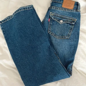 Blå Levis jeans - Säljer ett par klassiska blå Levis jeans i mycket bra skick. De är bootcut med en låg midja, vilket ger en snygg och bekväm stil. Perfekta för både vardag och fest! 🕺