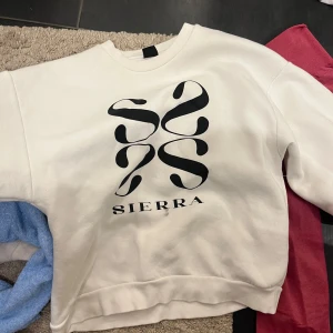 Vit sweatshirt från Sierra - Säljer en snygg vit sweatshirt från Sierra med ett coolt svart tryck på framsidan. Tröjan har en normal passform och är perfekt för både vardag och chill. Den är i mycket bra skick och passar perfekt till jeans eller mjukisbyxor. Perfekt för höst och vår!