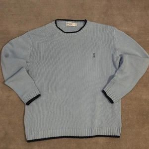 Ljusblå tröja från Yves Saint Laurent - Säljer en stilren ljusblå tröja från Yves Saint Laurent i 100% bomull. Tröjan har svarta detaljer vid hals och ärmslut samt en diskret logga på bröstet.