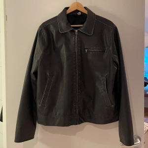 Grå biker jacka från H&M - Säljer en biker jacka i läderimitation från H&M i storlek M. Jackan har en dragkedja framtill och två fickor. Perfekt för höst och vår. Jackan är i mycket bra skick. 