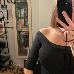 Svart ribbad topp från River Island - Snygg svart ribbad topp från River Island i storlek 10. Den har en offshoulder-design och trekvartsärmar, perfekt för både vardag och fest. Toppen är i mycket bra skick och passar bra till både jeans och kjol. 