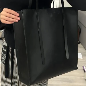 Svart axelväska  - Säljer en stilren svart axelväska från Even&Odd. Den har en enkel och elegant design med långa remmar, perfekt för vardagsbruk. Väskan är rymlig och passar till alla outfits. Perfekt för både jobb och skola:) inga defekter:)