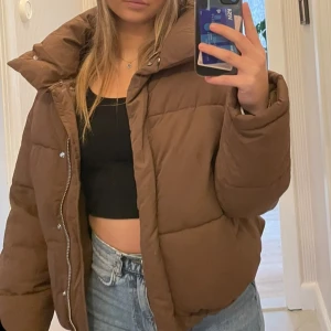 Brun pufferjacka - Säljer en snygg brun pufferjacka i mycket bra skick. Jackan har en dragkedja framtill och även knappar. Det är ingen luva på den, hör av dig om du har frågor eller vill ha mer bilder!