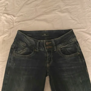 Mörkblå jeans från LTB - Snygga mörkblå jeans från LTB med låg midja och klassisk femficksdesign. Jeansen har en knappgylf och är perfekta för en avslappnad stil.