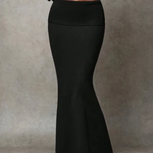 Svart långkjol - Snygg svart långkjol i ribbat material. Perfekt för både vardag och festliga tillfällen. Kjolen har en tight passform upptill och blir vidare nedtill, vilket ger en elegant siluett. Den är bekväm och stilren, lätt att matcha med olika toppar och accessoarer. 