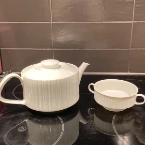 Vit tekanna och sockerskål - set från Rosenthal - Säljer en elegant vit tekanna och matchande skål från Rörstrand. Båda har ett stilrent räfflat mönster och är perfekta för en mysig fika. Tekannan har ett bekvämt handtag och ett lock, medan skålen har två små handtag. Perfekt för att servera te och tilltugg. Passar både till vardag och fest!