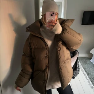 Brun dunjacka i storlek XS - Säljer en supermysig brun/khaki dunjacka i storlek XS. Perfekt nu till vintern då den nästan bara innehåller dun och har så gosig hög krage! Har både knappar och dragkedja. Förutom en liten vit fläck vid sidan av ryggen är den i suuperfint skick.  Kostar 2000kr ny!!