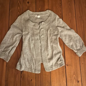 Grå vintage kofta - Jag säljer denna gråa vintage kofta med knappar och fina detaljer då den tyvärr inte passar mig🥲 Den har väldigt snygga och bekväma trekvarts ärmar! Den är som ny och från en gammal vintage HM kollektion! Den är i storlek XS men jag skulle säga ty den mer passar S och M! Pris kan som alltid diskuteras! Skriv om du har fler frågor!😊💕