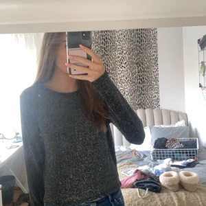 Svart glittrig tröja från H&M Divided - Säljer en svart glittrig tröja från H&M Divided i storlek XS. Perfekt för festliga tillfällen. Tröjan har långa ärmar och en bekväm passform. Använd ett fåtal gånger, så den är i mycket bra skick. Passar perfekt till både jeans och kjol!