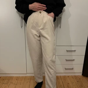 Beige manchesterbyxor - Säljer ett par snygga beige manchesterbyxor i mycket bra skick. De är högmidjade och har en normal passform som ger en stilren look. Perfekta för höst och vinter, och de har en klassisk rak stil. Byxorna är superbekväma och passar både till vardags och lite finare tillfällen.