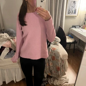 Rosa stickad tröja - Säljer en söt rosa stickad tröja med rund hals och långa ärmar. Perfekt för kyligare dagar och lätt att matcha med olika outfits. Tröjan har en mjuk och bekväm passform.