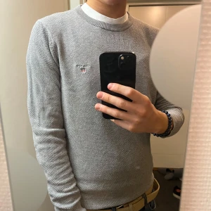 Grå tröja från GANT - Säljer en stilren grå tröja från GANT i premium bomull. Den har en liten broderad logga på bröstet och rund halsringning. Perfekt för både vardag och lite finare tillfällen. Tröjan är i mycket bra skick och passar perfekt till höst och vår.