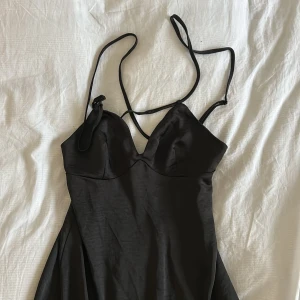 Svart axelbandslös klänning - Elegant svart klänning med smala axelband och formad byst. Perfekt för en stilren look. Från NAKD