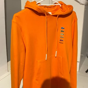 Orange hoodie från Lacoste x Polaroid - Säljer den super fina oranga hoodien från Lacoste i samarbete med Polaroid. Hoodien är i xs men skulle passa S och M. Aldrig anvönt. Endast testat! I nyskick. Pris kan diskuteras! 