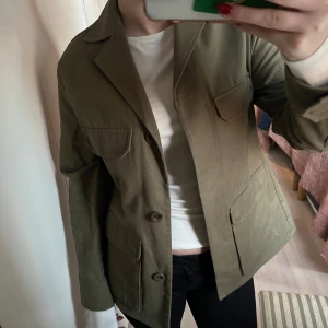 Olivgrön jeansjacka från COS - Säljer en stilren olivgrön jeans jacka från COS i storlek 34. Jackan är figursydd och sitter bra längst kroppen. Har även många fickor och knappar. Den är tyvärr för liten för mig och knappt använd. 